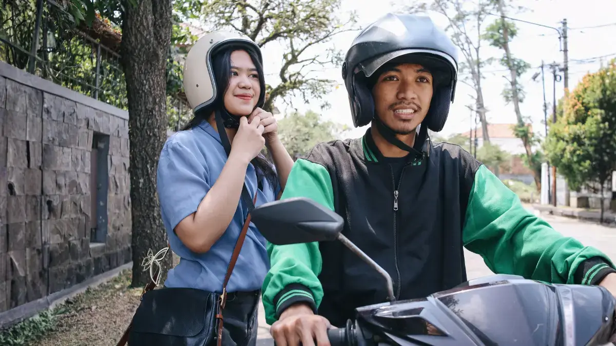 Gojek driver waiting on scooter with safety equipment