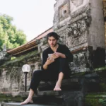 Escaping heat to use mobile phone at temple in Bali - essential gear for solo travelers