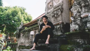 Escaping heat to use mobile phone at temple in Bali - essential gear for solo travelers
