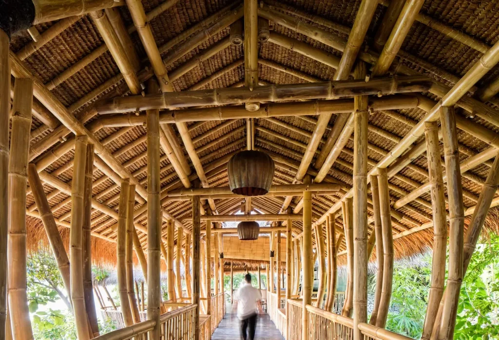 Bamboo-covered walkway with hanging lanterns and a person walking away