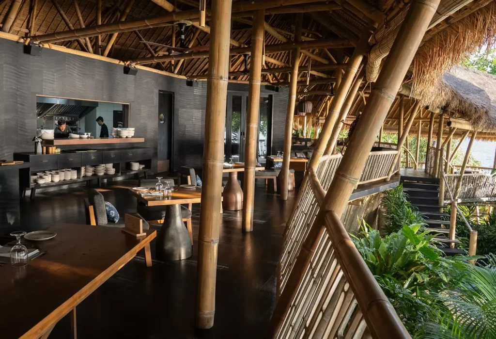Open-air bamboo restaurant with tables overlooking lush greenery and water