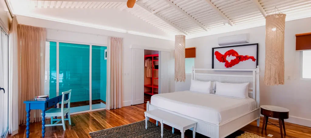 Bright bedroom with a white bed, blue desk, and sliding glass doors to a turquoise patio