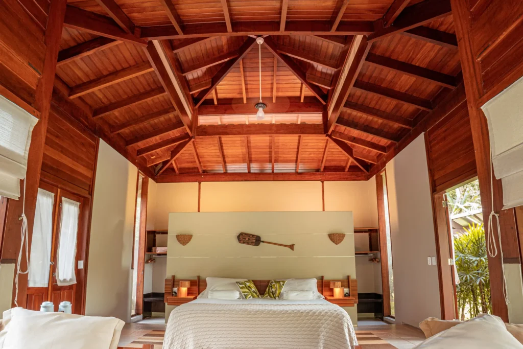 Wooden bedroom interior with a high vaulted ceiling and a large bed centered beneath it