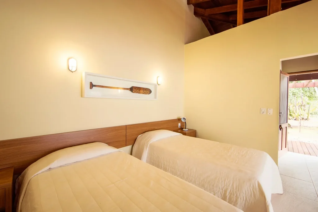 Twin beds in a bright room with an open door to a patio