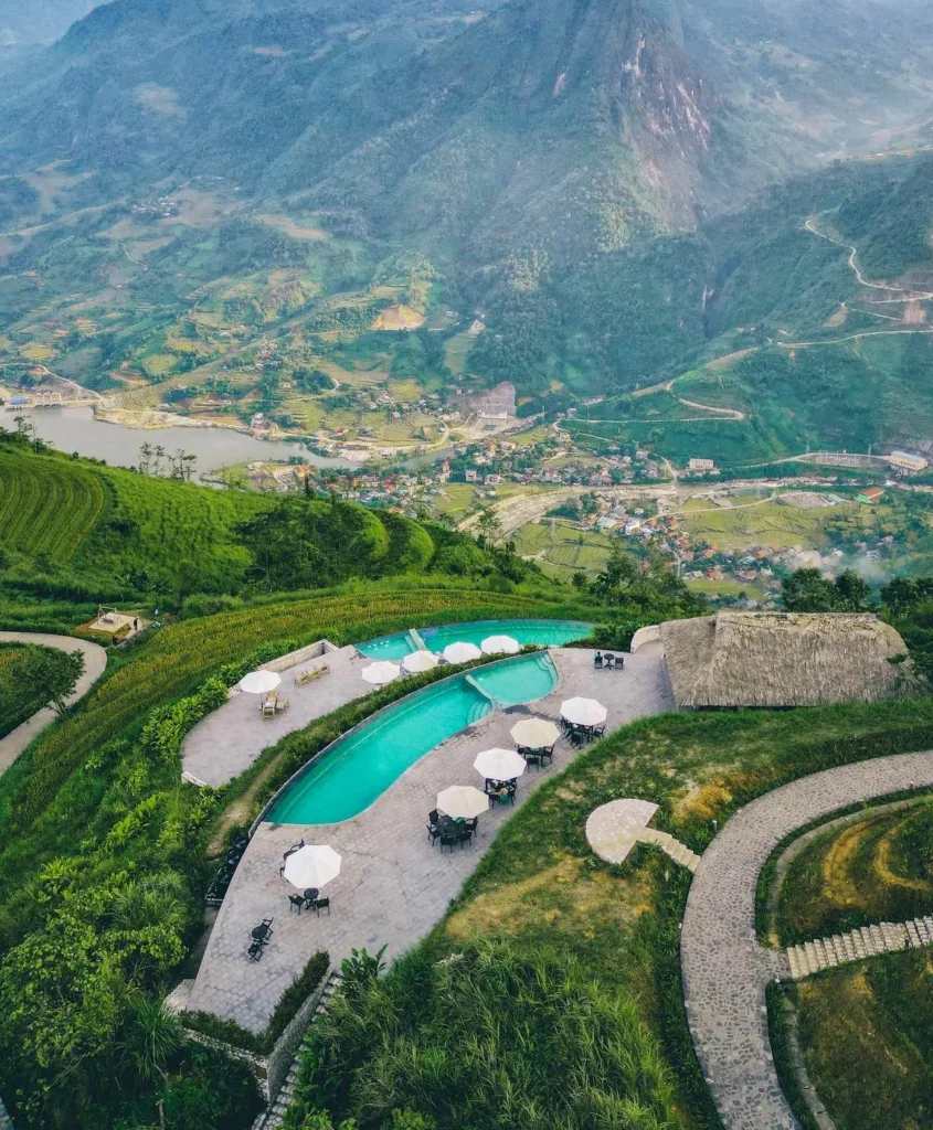 Mountain valley resort with an infinity pool and terrace overlooking terraced fields and a village
