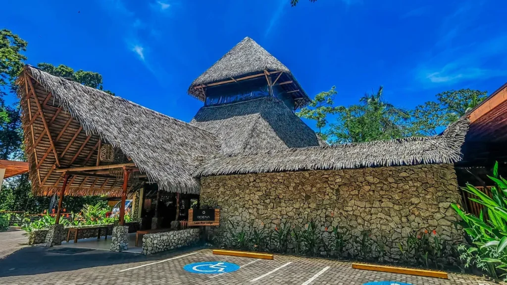 Thatched-roof lodge entrance with stone walls and accessible parking spaces