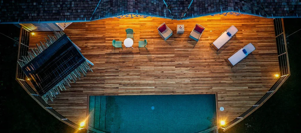 Overhead view of a wooden deck with lounge chairs, a small table, and a rectangular pool