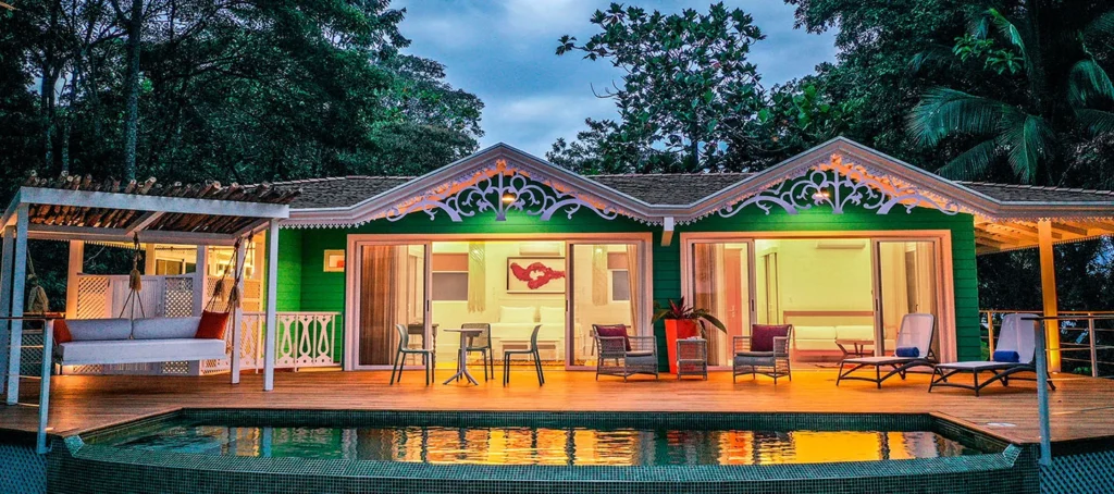 Tropical villa with a pool, deck, and lounge chairs at dusk