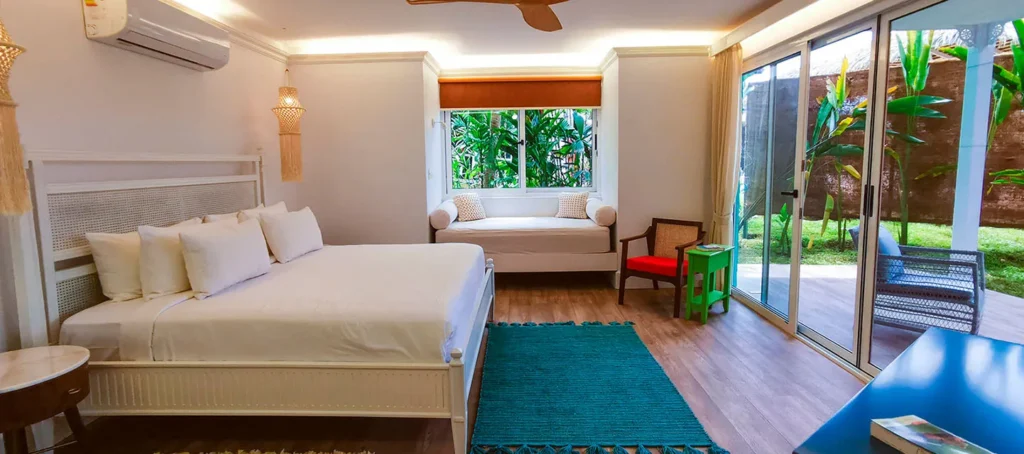 Bedroom with a large bed, window seat, and sliding glass doors to a patio and garden