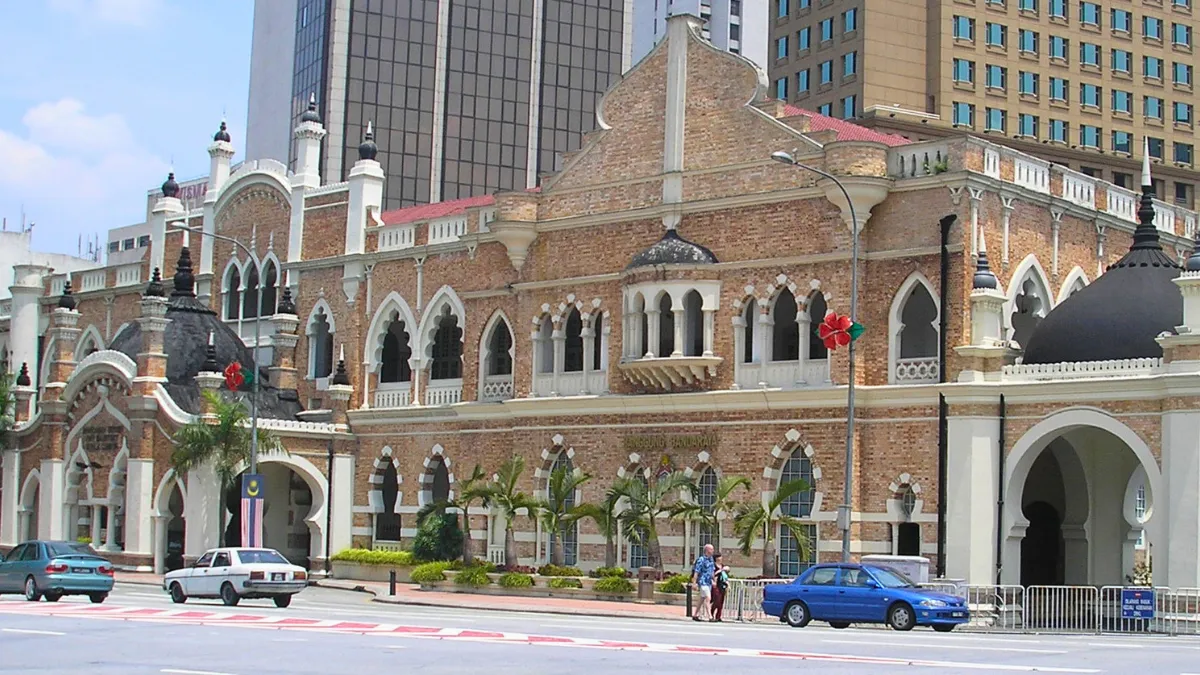 Historic brick building with arched windows and domed towers in a city street