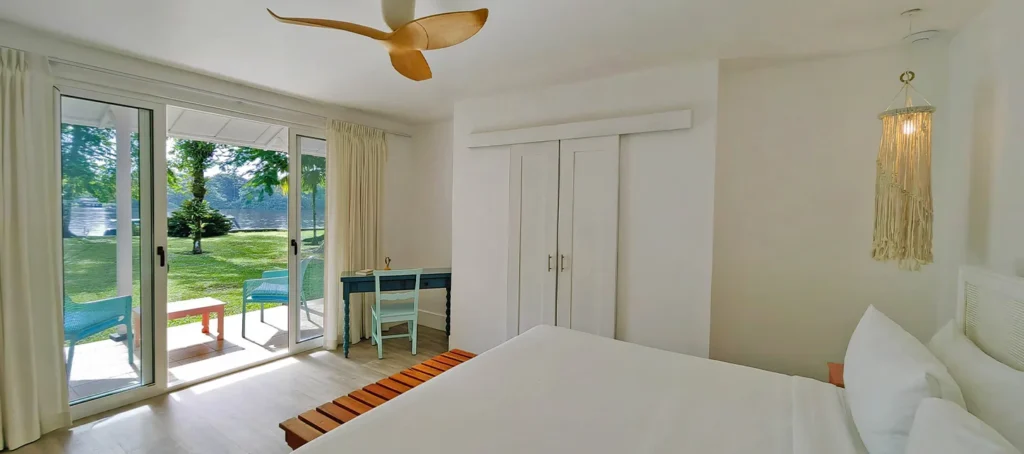 Bright bedroom with sliding glass doors opening to a lakefront patio and a small desk by the window