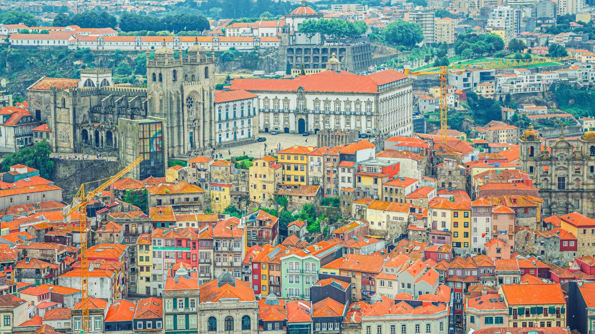 Aerial view of a historic city with red-tiled rooftops and a large cathedral complex