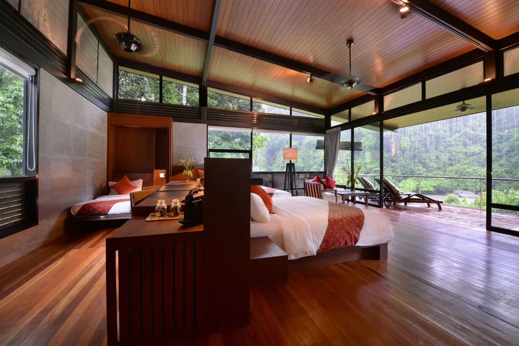 Open-air bedroom with two beds and a forest view