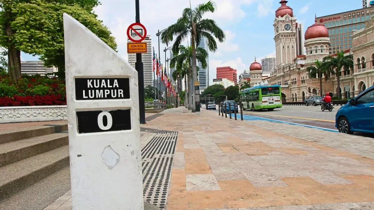 Kuala Lumpur marker with city street, palm trees, and historic buildings in the background