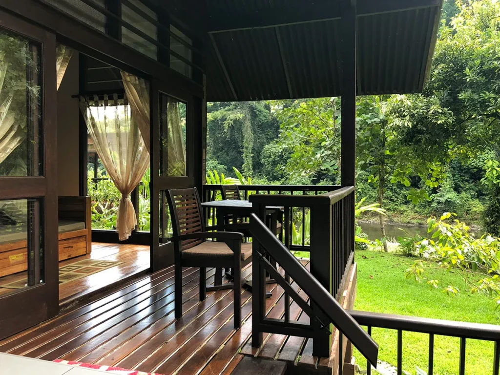 Wooden porch with chairs overlooking a lush green forest and river