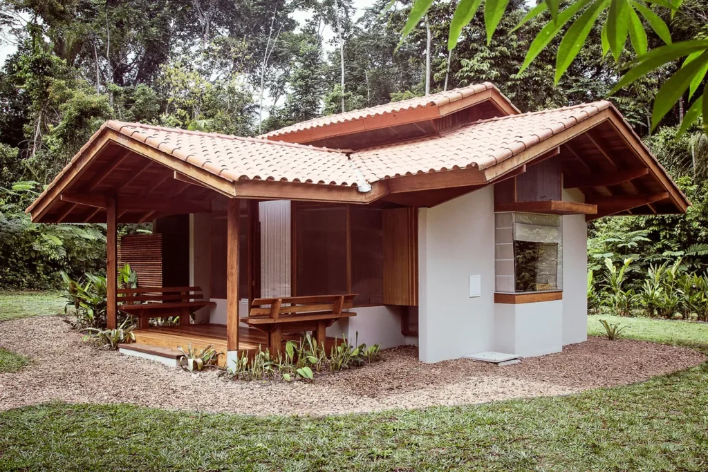 Small house with a tiled roof and wooden porch in a lush tropical setting