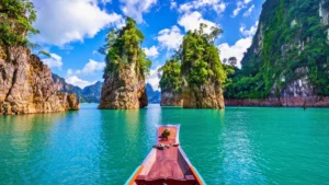 Long-tail boat on turquoise water between limestone cliffs and lush islands under a blue sky