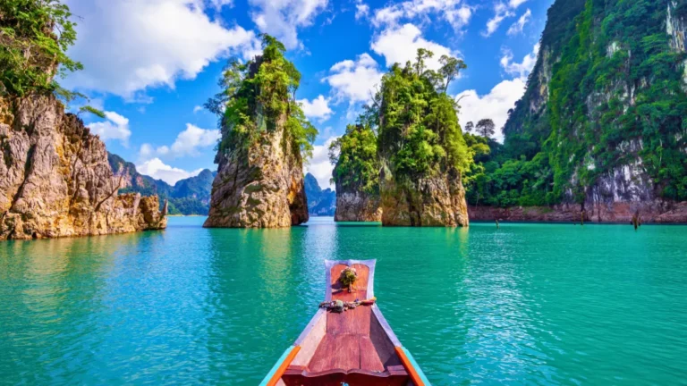 Long-tail boat on turquoise water between limestone cliffs and lush islands under a blue sky