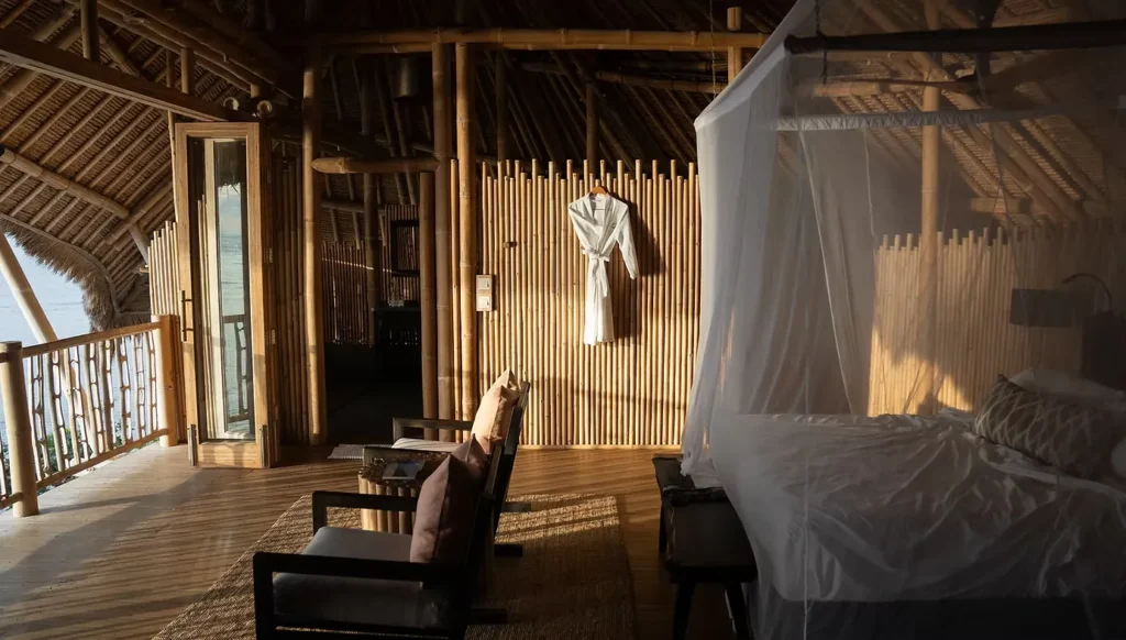 Open-air bamboo resort room with a canopy bed and ocean view