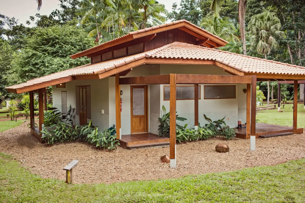 Tropical house with a tiled roof and wooden porch surrounded by lush palm trees