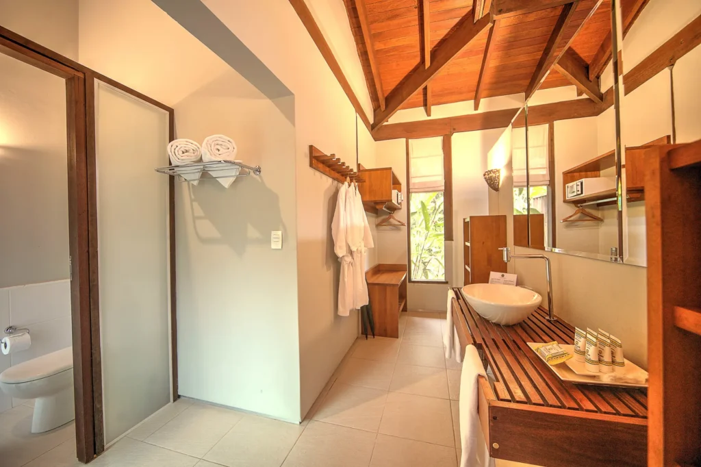 Bathroom with wooden ceiling, glass shower, vanity, and towels in a tropical-style room