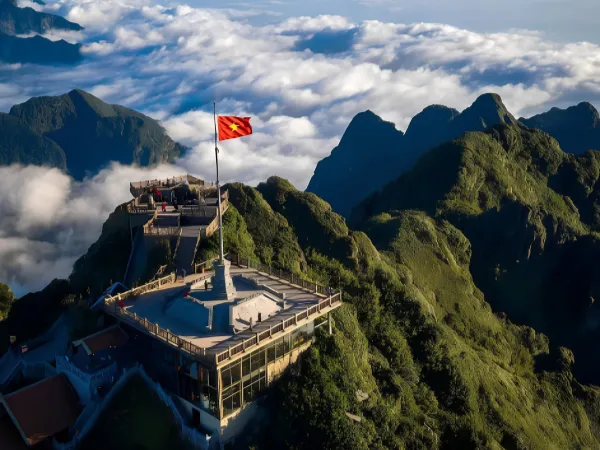Mountain summit viewpoint with a Vietnamese flag above the clouds