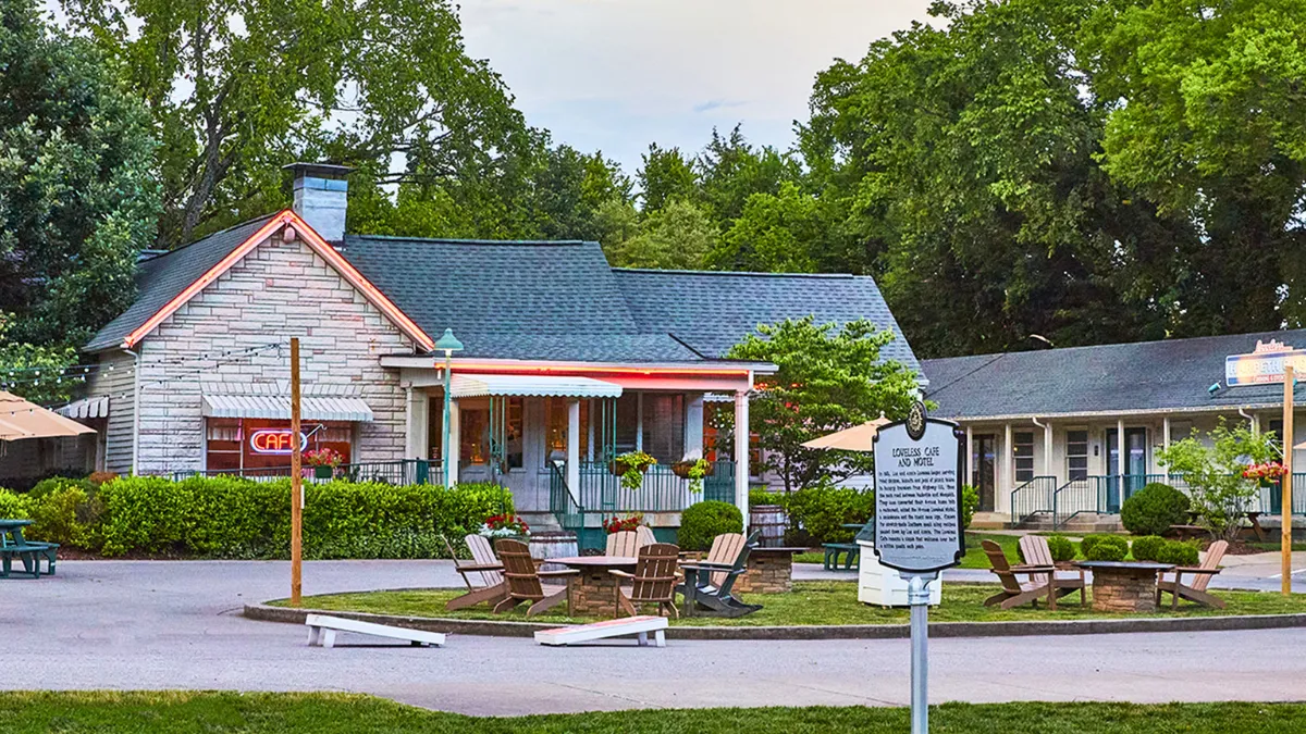 Historic roadside motel with a café, porch seating, and a sign in front