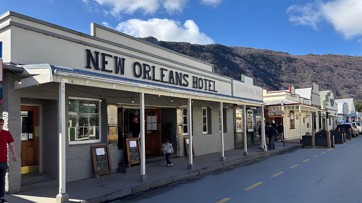 New Orleans Hotel storefront on a mountain-lined street under a blue sky