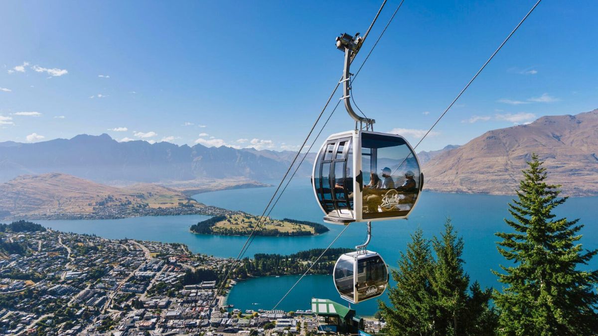 Gondola cabins overlooking Queenstown and Lake Wakatipu, surrounded by mountains and blue sky