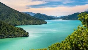 Turquoise lake winding through forested green mountains