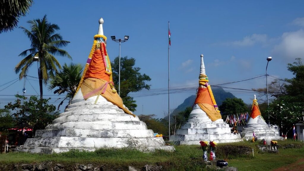 Decorated white Buddhist stupas beneath palm trees in Sangkhlaburi